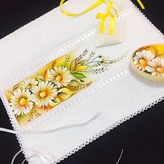 a table topped with white doily and yellow flowers next to a bowl filled with candy