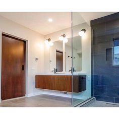 a bathroom with a glass shower door and wooden cabinet in front of the sink area