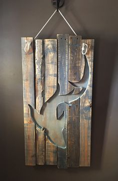 a metal deer head mounted to the side of a wooden wall hanging on a gray wall