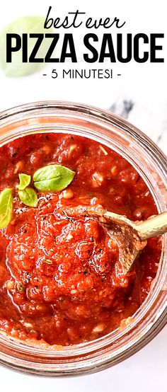 the best ever pizza sauce in a glass jar with a wooden spoon and basil sprig on top