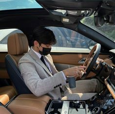 a man wearing a face mask sitting in the driver's seat of a car