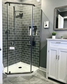 a walk in shower sitting next to a white cabinet and sink on top of a tiled floor