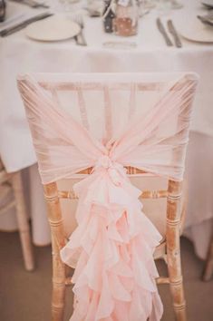 the back of a chair with a pink ruffled sash on it's seat