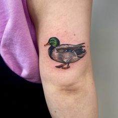 a woman's arm with a small tattoo of two ducks on the left side