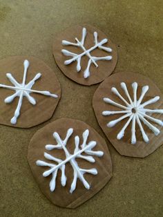 four snowflakes made out of brown paper on the ground