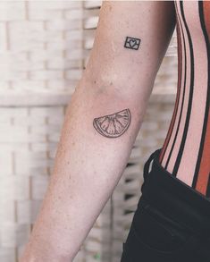 a woman's arm with a tattoo on it that has a slice of fruit