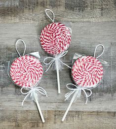 three red and white lollipops are on a wooden table with twine