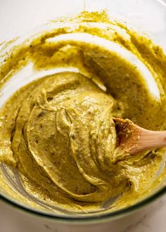 a bowl filled with green sauce and a wooden spoon