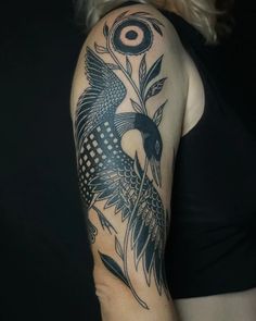 a woman's arm with a bird and flower tattoo design on the left shoulder