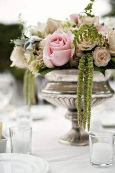 a vase filled with lots of flowers on top of a white tablecloth covered table