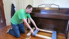 a man in green shirt working on a wooden bench with two pieces of plywood