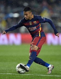 a man kicking a soccer ball on top of a field