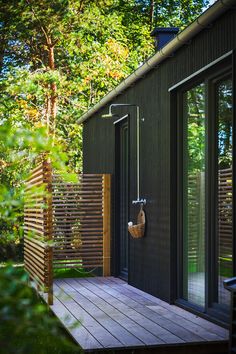 the outside of a house with wooden decking and sliding glass doors that lead out onto a wooded area