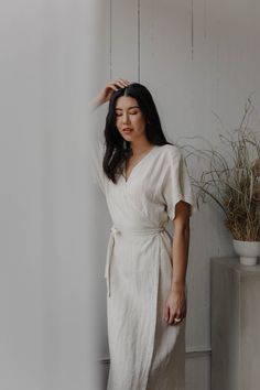 "This carefully tailored lightweight wrap dress has a cocktail length, roomy short sleeves, a cinched waist and an A-line skirt. It also has back darts, a built in wrap belt and invisible pockets. We used the highest quality linen sourced in Canada which is breathable, soft and pre washed with an antique finish. Like all of our pieces, this dress is handmade by us to order in our studio in British Columbia. Please provide us with your measurements so we can ensure the perfect fit. If you have an Dress Capsule Wardrobe, Casual Wedding Guest Dress, Linen Skirt Outfit, Casual Wedding Guest, White Linen Skirt, Casual Wedding Guest Dresses, Long Wrap Dress, Wrap Dress Pattern, Linen Wrap Dress