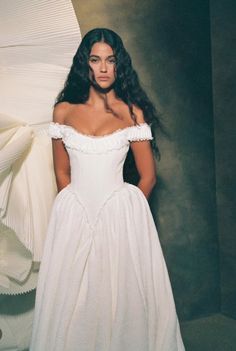 a woman in a white dress standing next to an umbrella