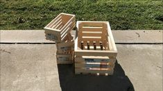 three wooden crates stacked on top of each other in the middle of a sidewalk with grass behind them