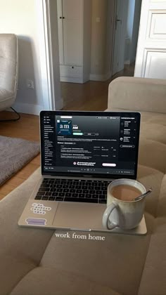 an open laptop computer sitting on top of a wooden table next to a cup of coffee