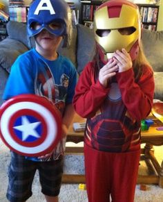 two children dressed up as captain america and iron man standing in front of a couch