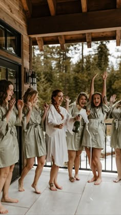 a group of women standing next to each other in front of a door with their hands up