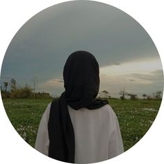 a person wearing a black scarf standing in a field