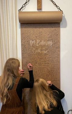 two women are writing on a cork board