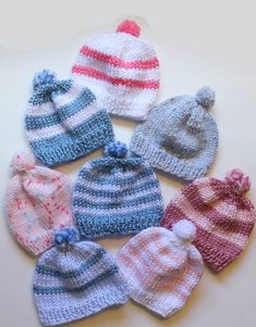 six knitted hats are arranged on a table