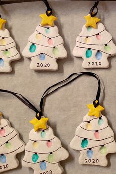 six ceramic christmas tree ornaments are hanging on a tray with black string and yellow stars