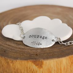 It only takes one little word to touch someone’s heart.This inspirational word bracelet makes a memorable gift idea that your recipient is sure to cherish. Artistically designed to perfection, it features a large oval shaped pendant stamped with the word “courage” and a whimsical leaf motif. Suspended from coordinating chain, it features a delicately hand hammered edge that adds layers of character. When worn, it caresses the top of your wrist beautifully and is sure to become a treasured access Meaningful Adjustable Charm Bracelet, Inspirational Sterling Silver Friendship Bracelets, Meaningful Faith-inspired Bracelet Jewelry, Meaningful Sterling Silver Friendship Bracelets, Inspirational Engraved Bracelets For Everyday, Inspirational Engraved Everyday Bracelets, Everyday Inspirational Engraved Bracelets, Hand Stamped Sterling Silver Friendship Bracelets, Inspirational Nickel-free Bracelets As Gift