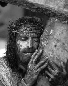 jesus carrying the cross with his hands and face covered in mud, black and white photograph