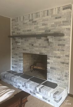 a brick fireplace in the middle of a room with a bed and pillows on it