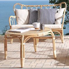 a wicker couch sitting on top of a patio next to a table with coffee