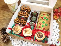 a box filled with assorted cookies and pretzels next to a cup of coffee