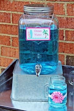 there is a glass jar with water in it on top of a metal tray next to a brick wall