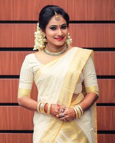 a woman in a white and yellow sari with her hands on her hips, posing for the camera