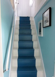 blue and white stairs leading up to the first floor in a house with framed pictures on the wall