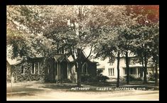 an old black and white photo of a house with trees in the front yard,