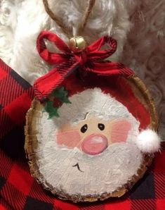 a wooden ornament with a santa clause on it's face and a red ribbon