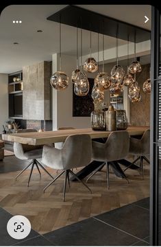 a dining room table with chairs and lights hanging from it's centerpieces