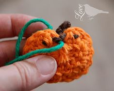 someone is holding a tiny crocheted pumpkin ornament