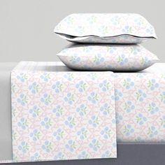 three pillows stacked on top of each other next to two folded sheets and one pillow