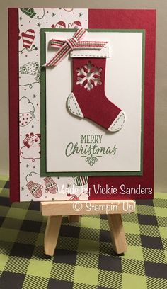 a handmade christmas card with a stocking hanging from the front, on a wooden easel