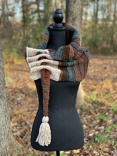 a black mannequin with a scarf on top of it in front of trees