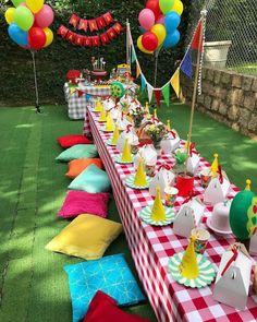 a long table covered in lots of colorful balloons and paper hats on top of it