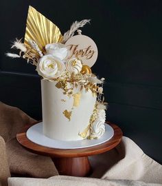 a white and gold wedding cake on a wooden stand