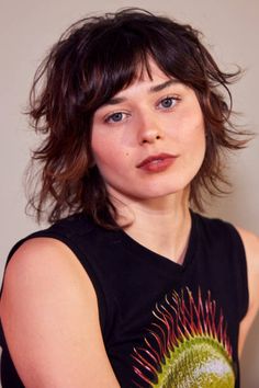 a close up of a person wearing a black shirt and holding a cell phone in her hand