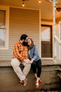 a man and woman sitting on the front porch of a house smiling at each other