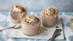 three desserts are sitting on a tray with spoons