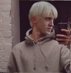 a young man with blonde hair is taking a selfie in front of a mirror