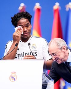 a man wiping his nose next to another man at a podium