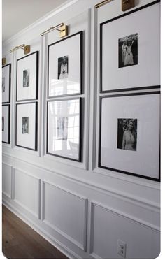 a white wall with black and white pictures on the walls, framed in gold frames